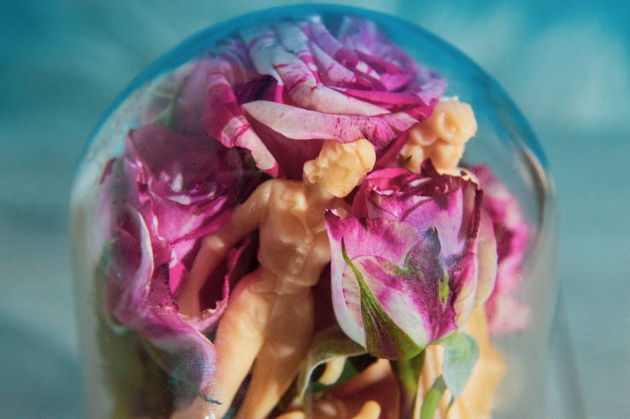 roses and cream colored plastic figures beneath glass dome